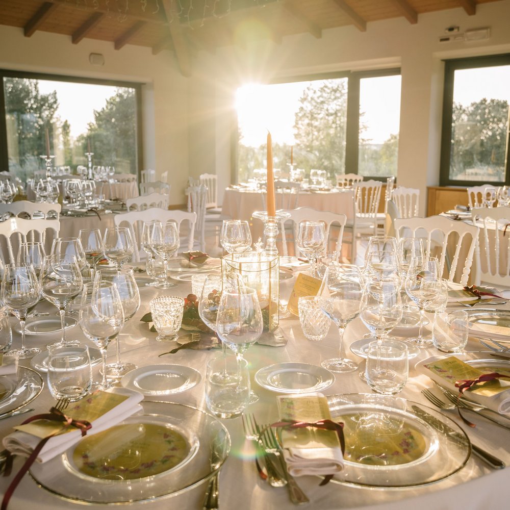 Valle di Assisi: un resort per matrimoni ad Assisi Tavolo elegante apparecchiato per evento con vetri e candela al tramonto