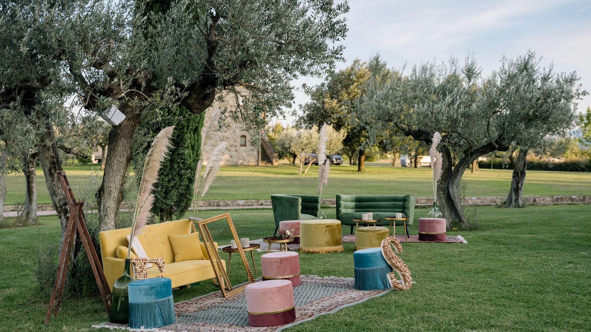 Valle di Assisi: un resort per matrimoni ad Assisi Area salotto colorata all'aperto in un giardino con alberi d'ulivo