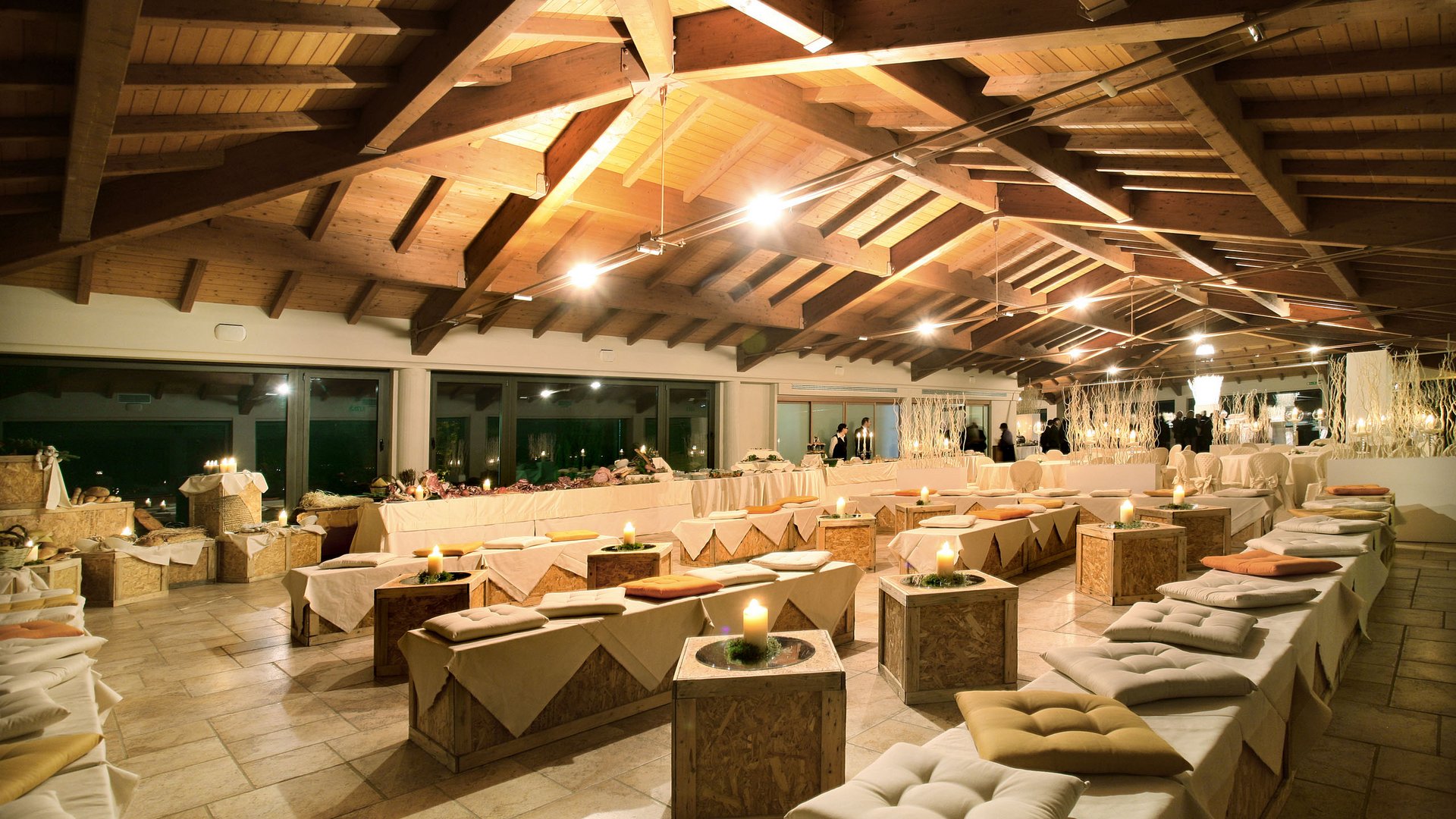 Valle di Assisi: un resort per matrimoni ad Assisi Sala elegante con tavoli e panche illuminate da candele per evento