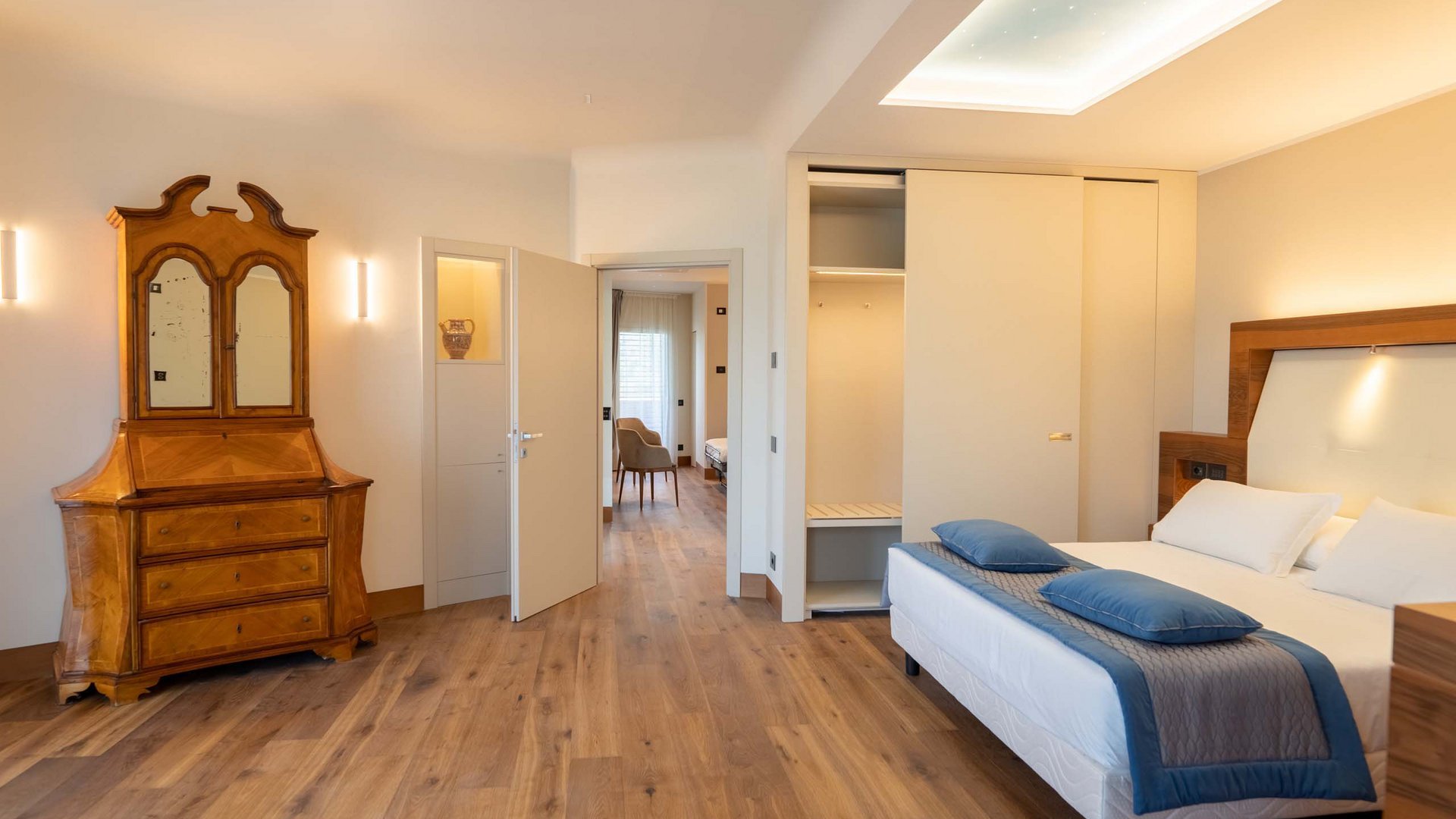 Hotel a 10 minuti di macchina da Assisi e la Basilica di San Francesco e il suo centro storico, 3 minuti di macchina dalla Porziuncola Camera da letto moderna con letto matrimoniale, armadio bianco e cassettiera vintage