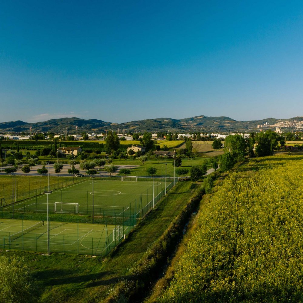Vacanze in Umbria, vacanze di pienezza Campi sportivi verdi vicino a campi gialli e colline sotto un cielo azzurro