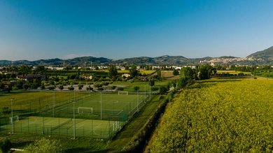 Perugia ha un Centro Meeting e Congressi d'eccezione: ai piedi di Assisi in Umbria Campi sportivi verdi vicino a campi gialli e colline sotto un cielo azzurro