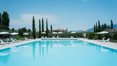 A holiday near Assisi: activities galore Large outdoor swimming pool with white loungers and umbrellas