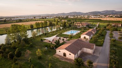 Perugia ha un Centro Meeting e Congressi d'eccezione: ai piedi di Assisi in Umbria Veduta aerea di azienda agricola con piscina e lago circondata da campi verdi e montagne