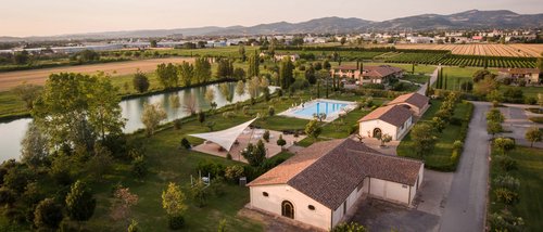 Assisi Cantico SPA - DaySPA in Umbria ad Assisi, la provincia di Perugia più bella. Percorsi Benessere Massaggi Idee Regalo per Adulti e Bambini Veduta aerea di azienda agricola con piscina e lago circondata da campi verdi e montagne