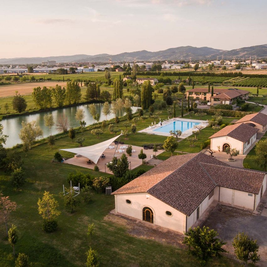 Resort bei Assisi im Country-Style Luftaufnahme eines Bauernhofs mit Pool und See, umgeben von grünen Feldern und Bergen