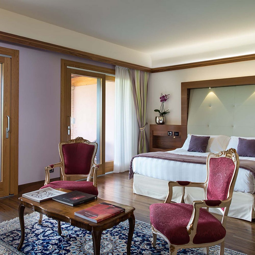 Hotel a 10 minuti di macchina da Assisi e la Basilica di San Francesco e il suo centro storico, 3 minuti di macchina dalla Porziuncola Camera elegante con letto grande, poltrone rosse e vista sulla terrazza