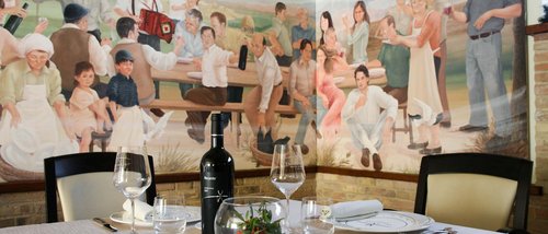 A Santa Maria degli Angeli - Assisi ( Perugia ) Centro Congressi e Meeting d'eccezione? I tuoi eventi vista Assisi Umbria Tavolo apparecchiato con vino davanti a murales di persone in festa