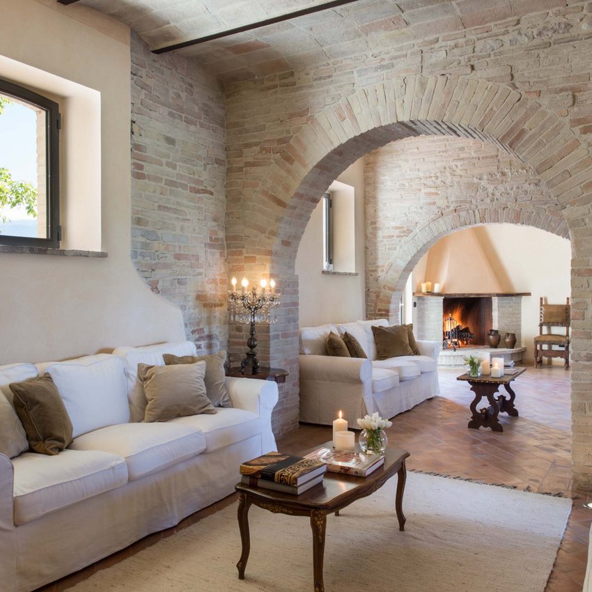 Resort bei Assisi im Country-Style Rustikales Wohnzimmer mit Backsteinbögen, weißen Sofas und brennendem Kamin