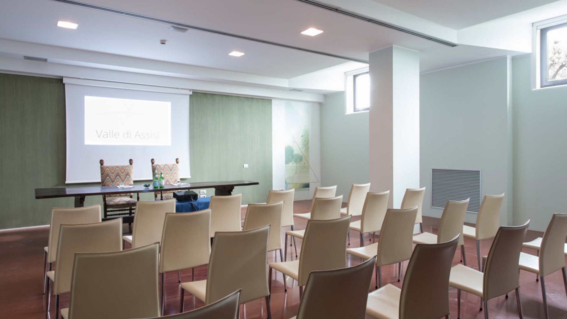 A Santa Maria degli Angeli - Assisi ( Perugia ) Centro Congressi e Meeting d'eccezione? I tuoi eventi vista Assisi Umbria Sala conferenze vuota con sedie disposte e proiettore acceso