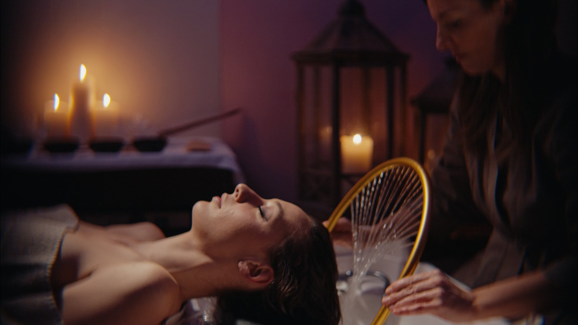 Questo rituale orientale unisce la cura di capelli a massaggi di viso, testa, cervicale, addome e braccia. Donna che riceve trattamento spa per capelli in ambiente rilassante con candele