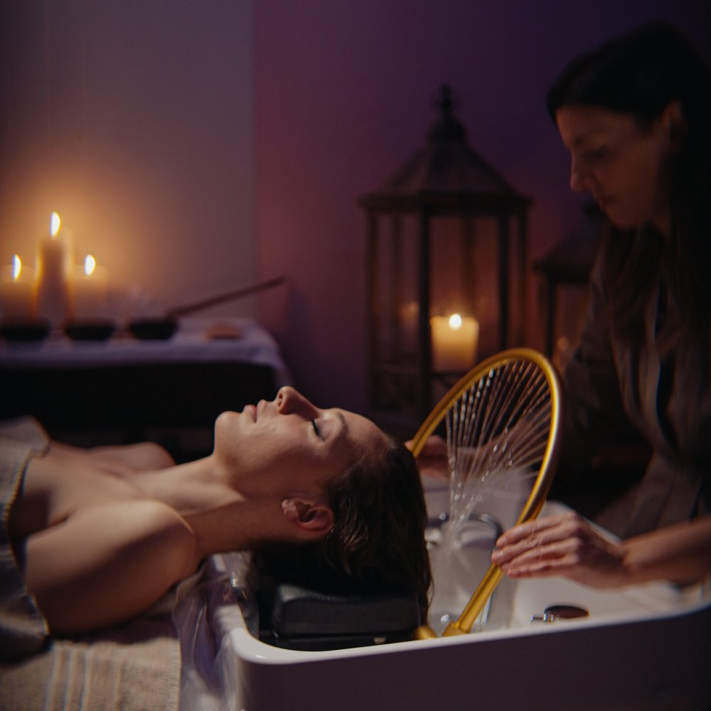 Ponte dell'Immacolata a Valle di Assisi Donna che riceve trattamento spa per capelli in ambiente rilassante con candele