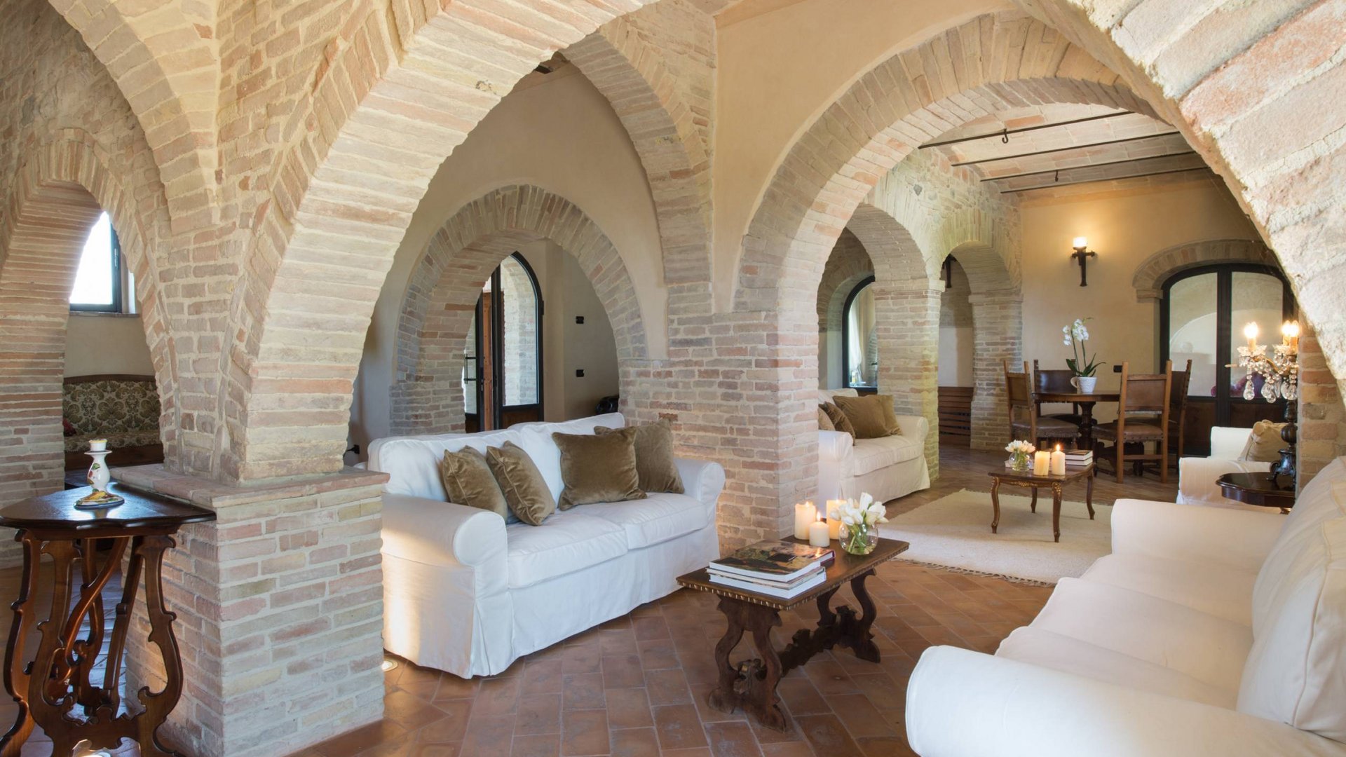 Ferienhaus in Umbrien mit Pool: in unserem Resort Rustikales Wohnzimmer mit Backsteinbögen und weißen Sofas