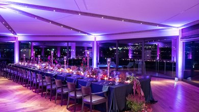 Perugia ha un Centro Meeting e Congressi d'eccezione: ai piedi di Assisi in Umbria Tavolo lungo allestito per cena elegante con luci viola e decorazioni floreali