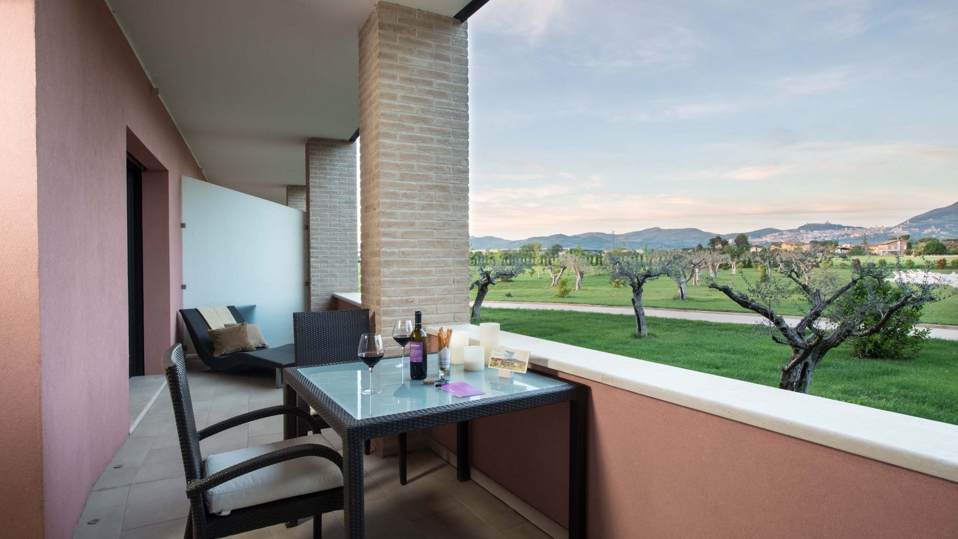 Urlaub in Umbrien? Und noch viel mehr! Terrasse mit Tisch und zwei Weingläsern mit Blick auf Olivenhain und Hügel