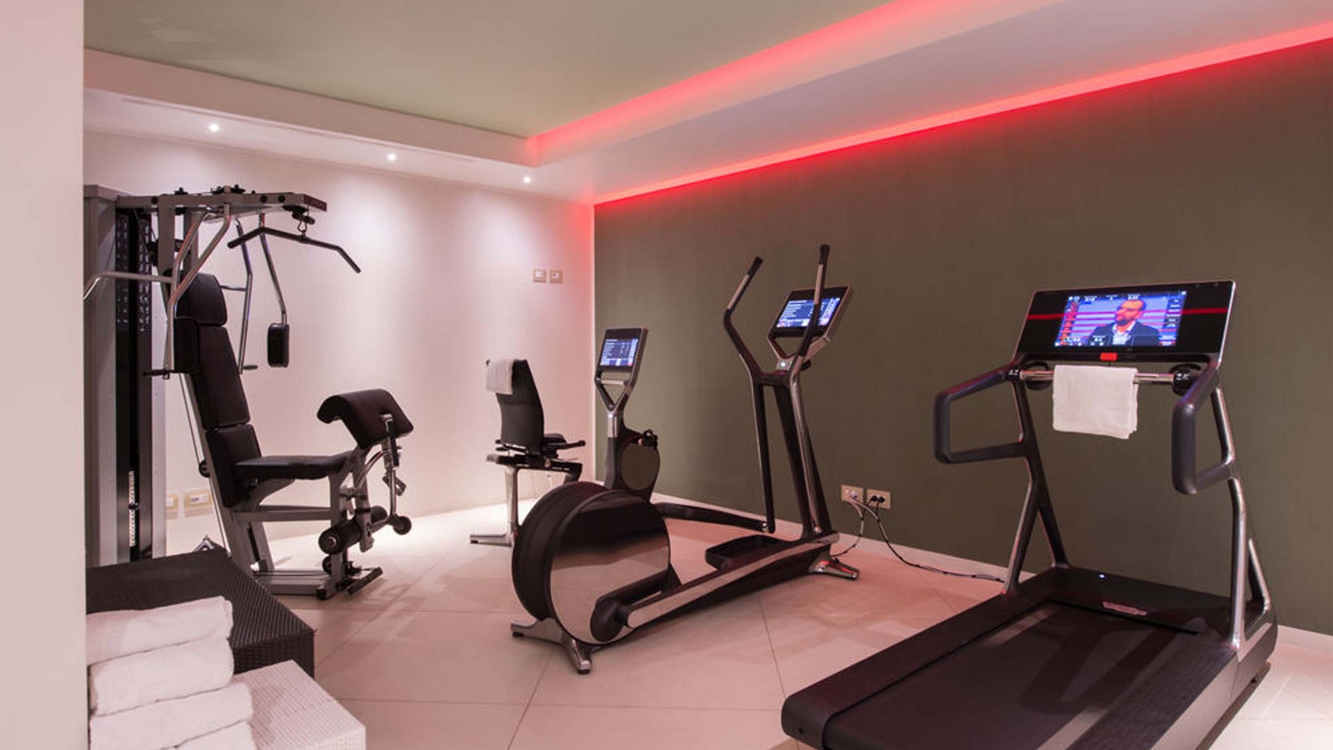 A hotel with spa for families with fitness area Modern gym with treadmill, exercise bikes, weight machine, and red LED lighting