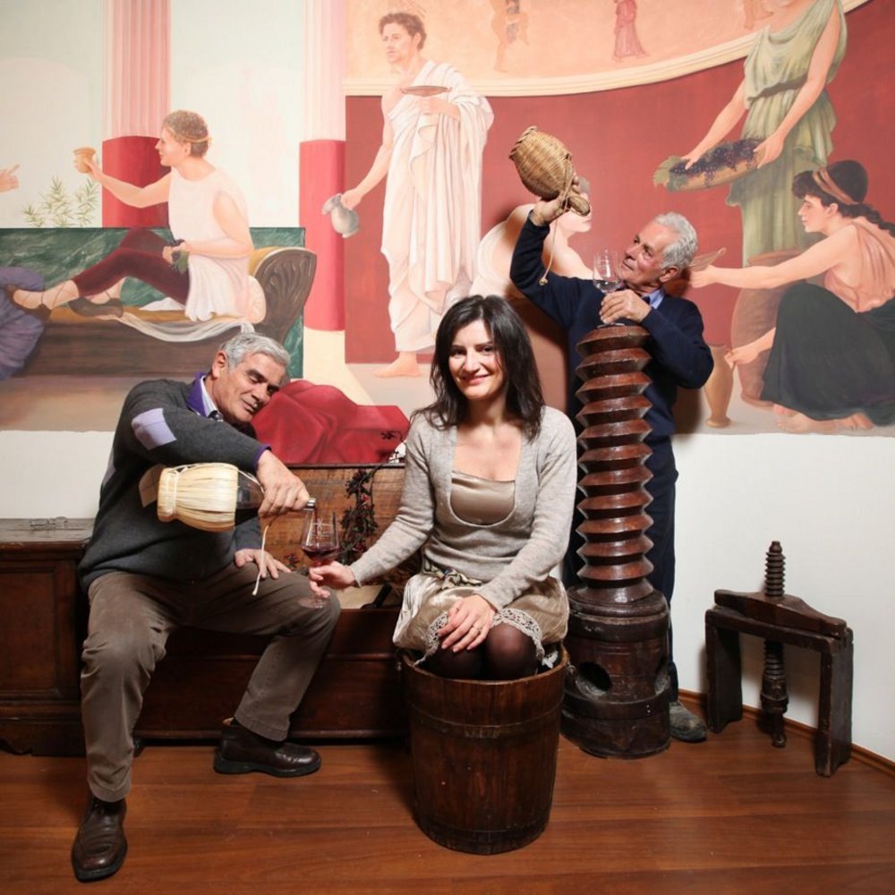 Halloween e Ognissanti Olio Nuovo, Vini e Relax nella Perugia più bella Due uomini versano vino mentre una donna siede in un secchio di legno a una festa