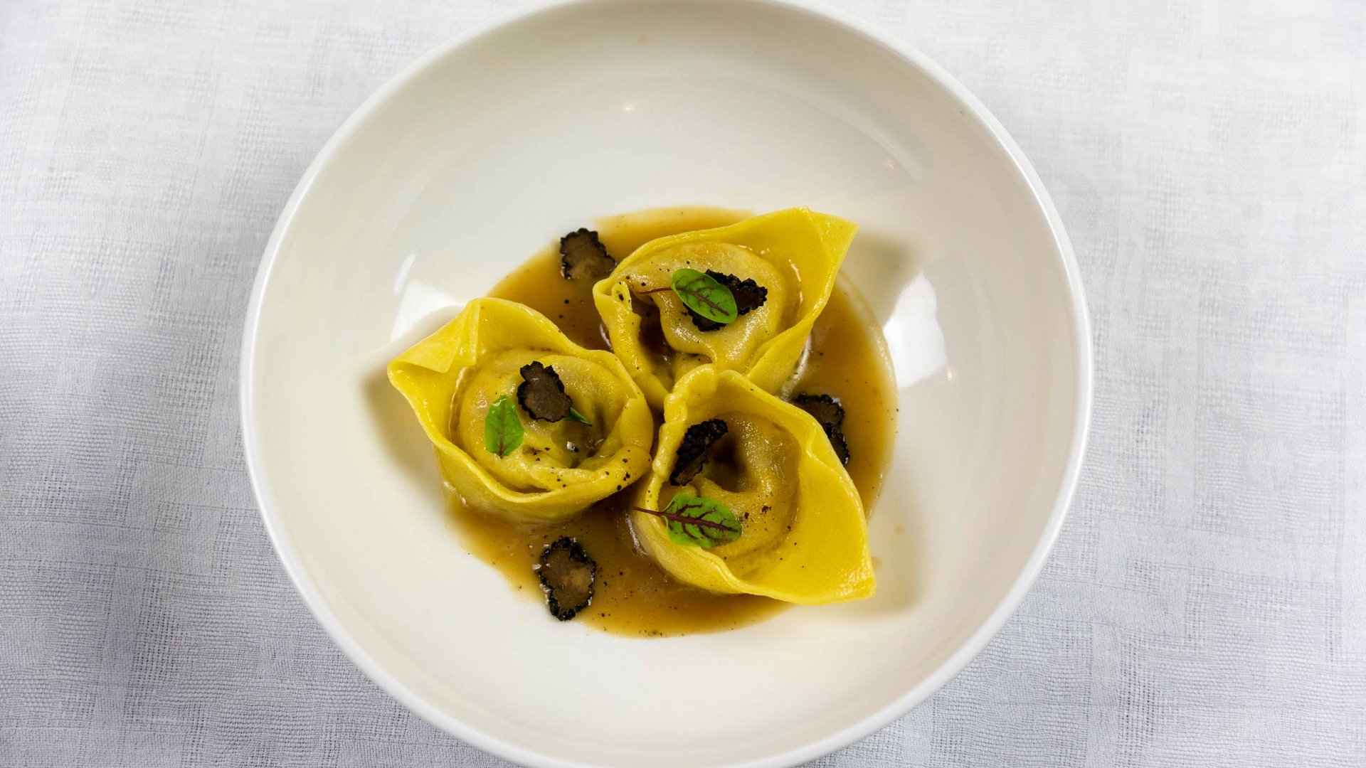 Umbrien: Unterkunft mit Restaurant Drei Tortellini mit Sauce und Trüffel auf weißem Teller