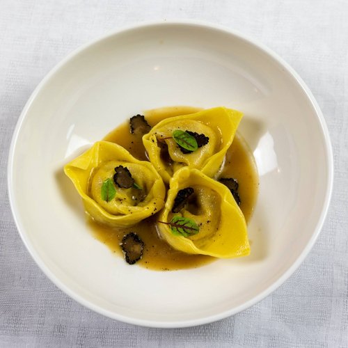 Die Mission des Valle di Assisi Drei Tortellini mit Sauce und Trüffel auf weißem Teller