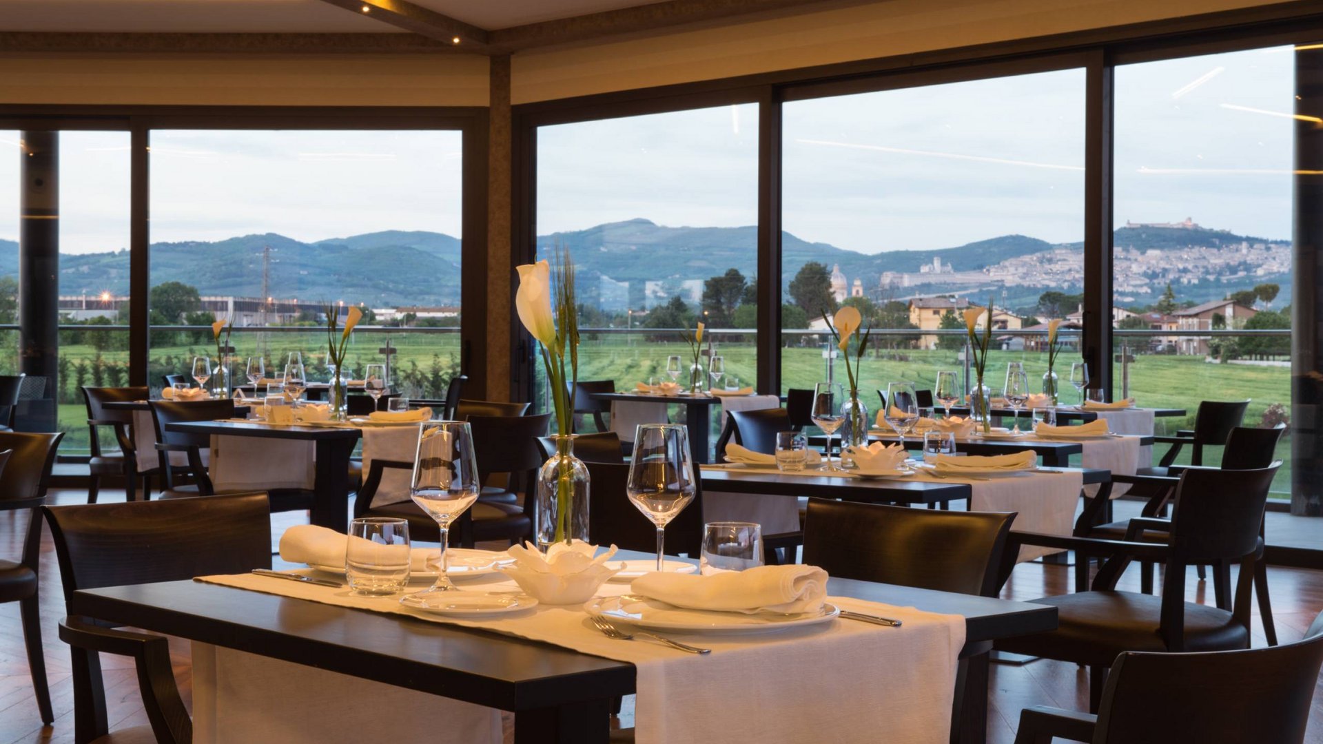 Hotel a 10 minuti di macchina da Assisi e la Basilica di San Francesco e il suo centro storico, 3 minuti di macchina dalla Porziuncola Ristorante elegante con tavoli apparecchiati e vista sulle colline