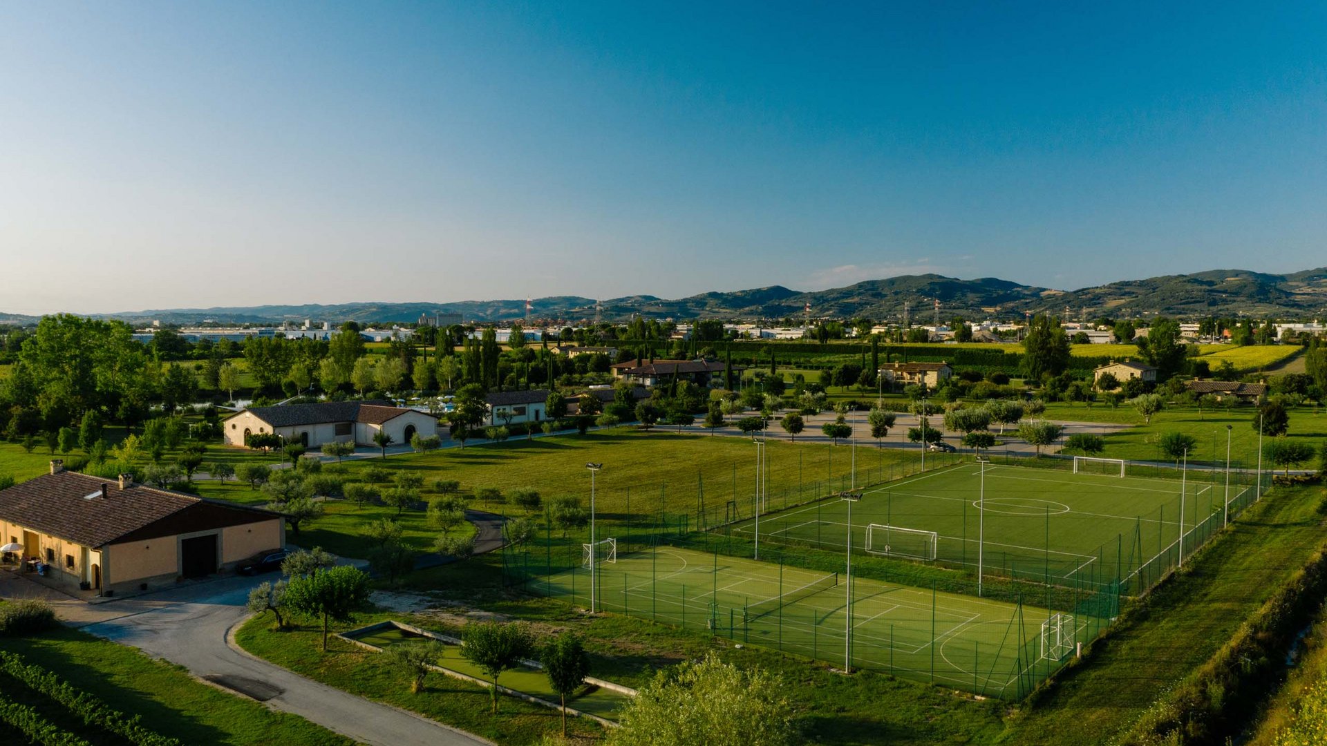 Urlaub in Umbrien? Und noch viel mehr! Sportplätze in grüner Landschaft mit Bergen im Hintergrund