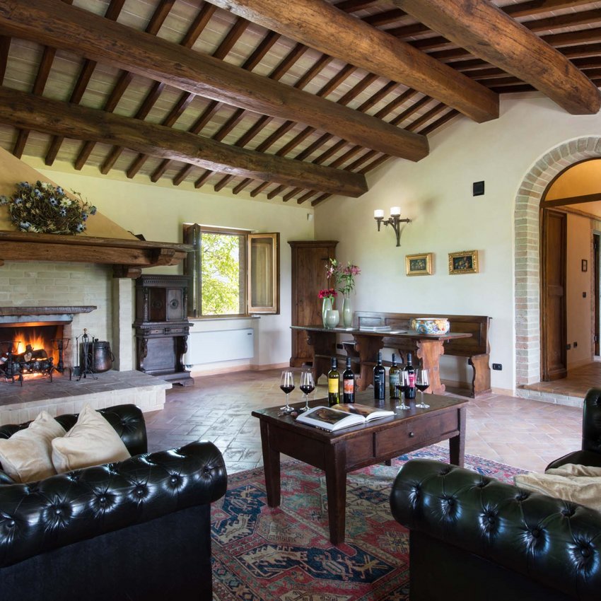 Resort bei Assisi im Country-Style Rustikales Wohnzimmer mit Kamin, Ledersofas und Tisch mit Weinflaschen