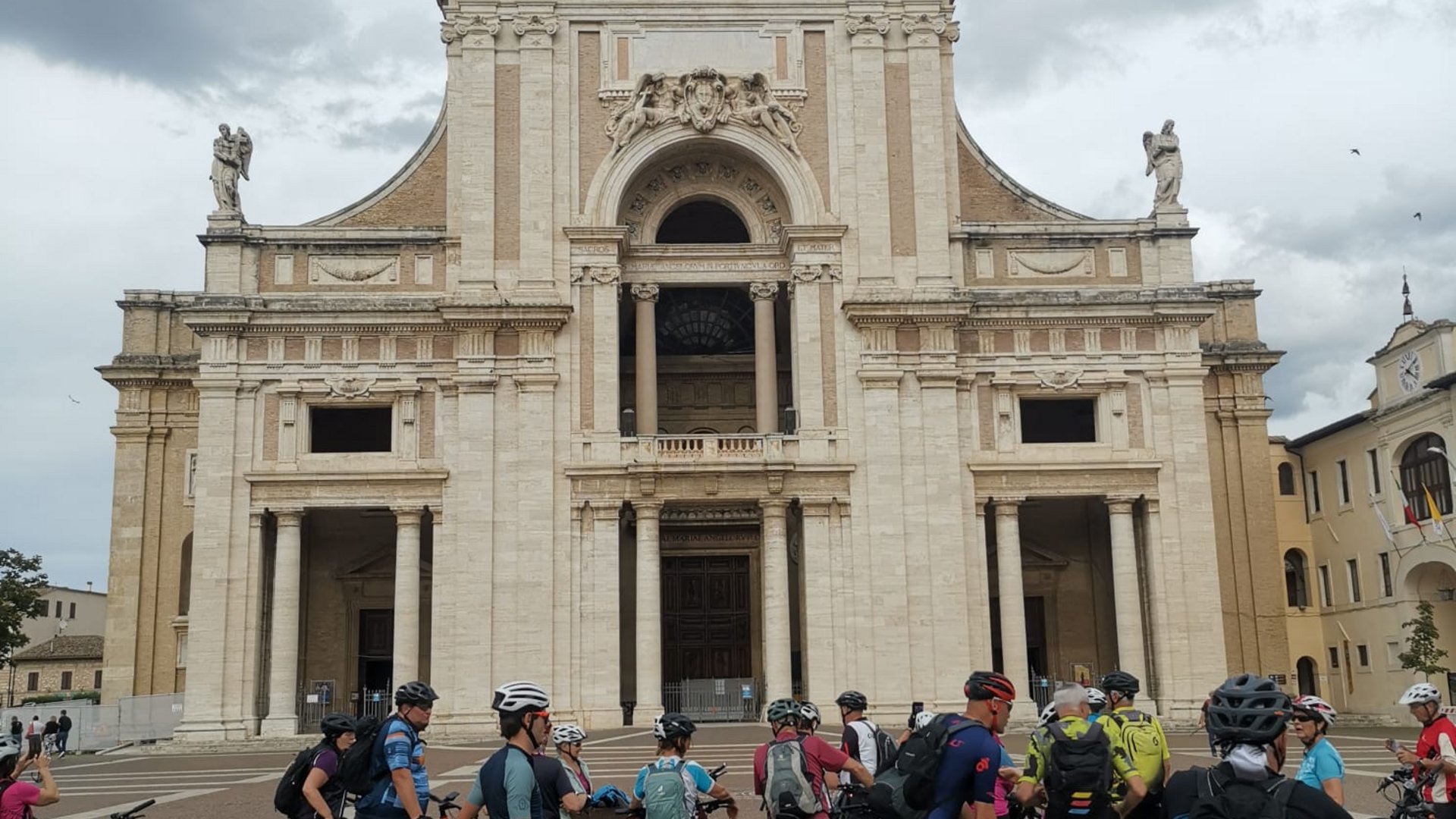 A holiday near Assisi: activities galore Group of cyclists in front of large historic church with golden statue on top