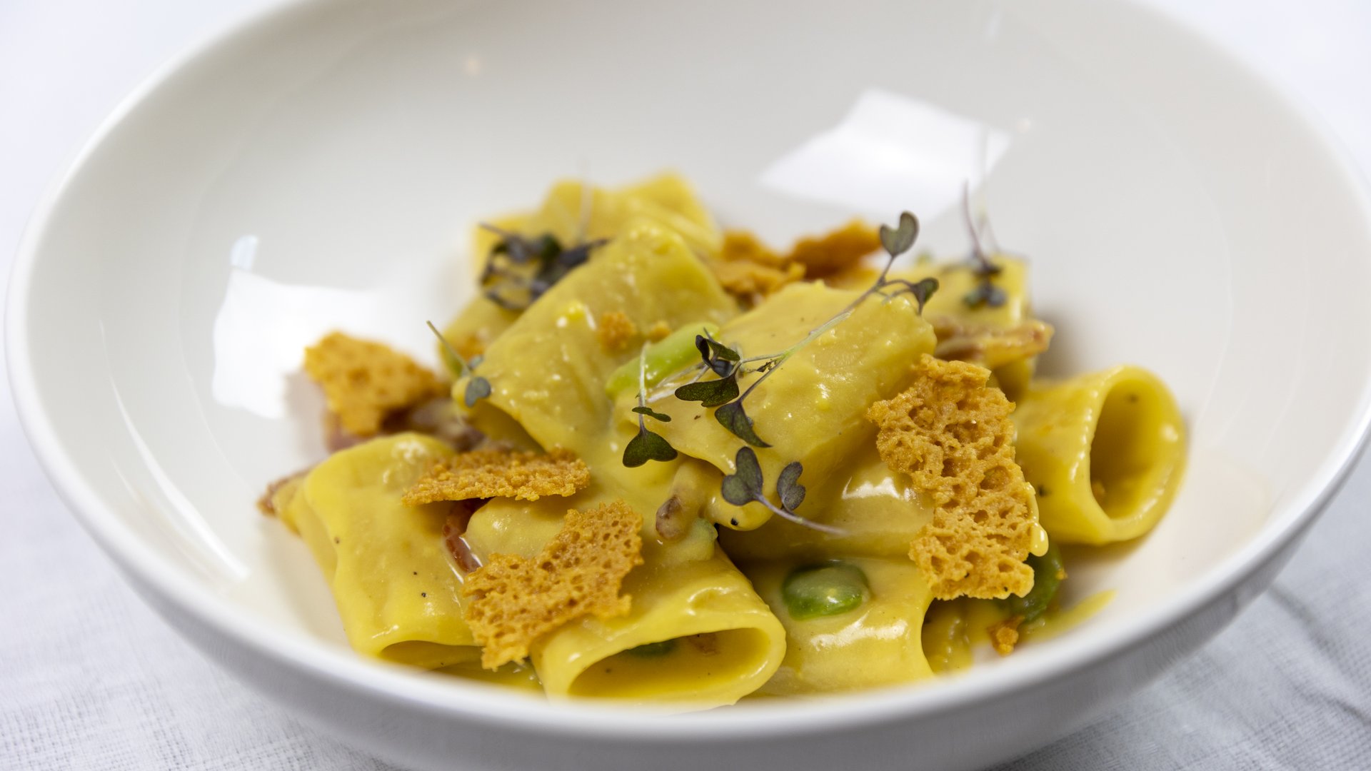 Assisi: Unterkunft mit Restaurant Kurze Pasta mit Sauce, frischen Kräutern und knusprigen Brotresten in weißer Schüssel