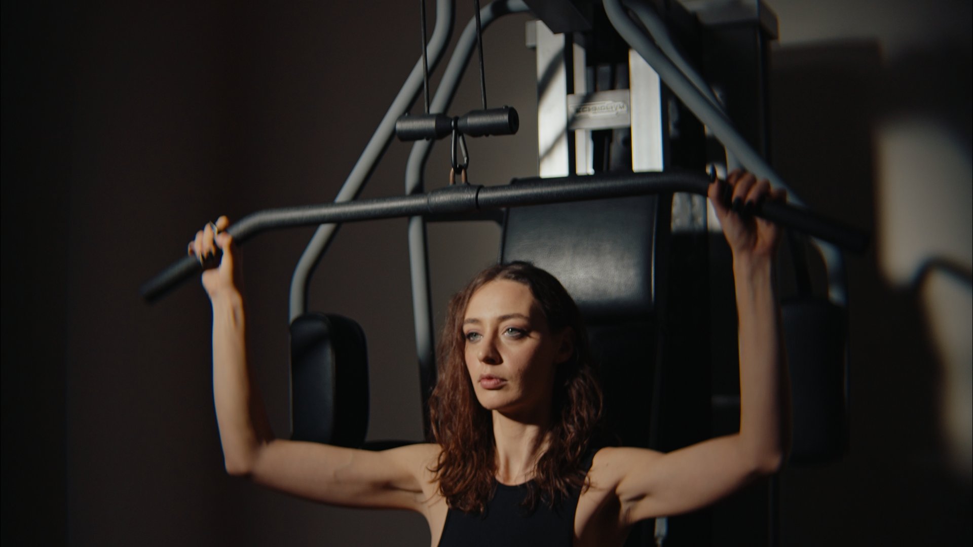 Donna che si allena con macchina per trazioni in palestra