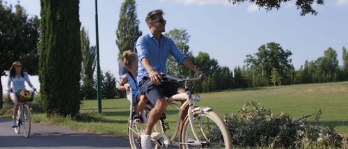 A Santa Maria degli Angeli - Assisi ( Perugia ) Centro Congressi e Meeting d'eccezione? I tuoi eventi vista Assisi Umbria Uomo in bicicletta con bambina seduta dietro durante una passeggiata in un parco soleggiato