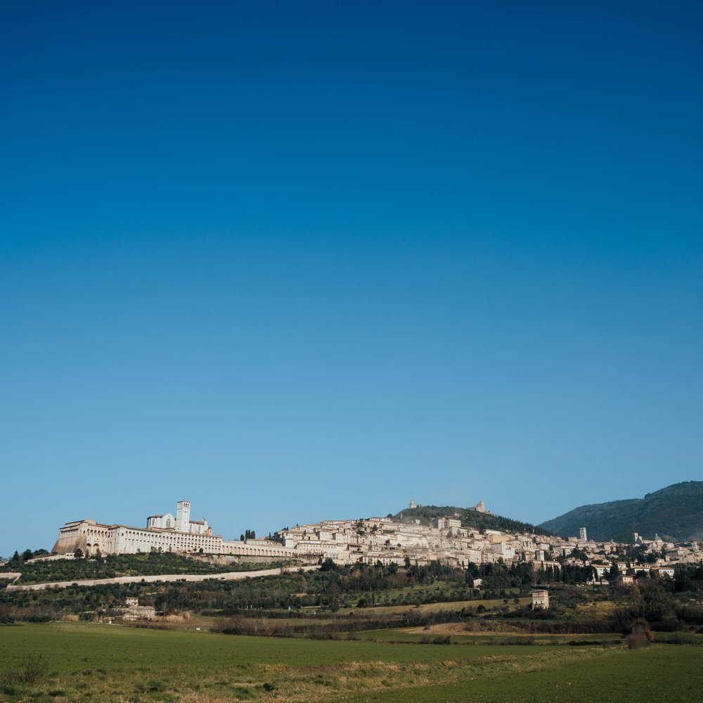 Guida all’Ostensione di San Francesco (Febbraio - Marzo 2026) Veduta panoramica di Assisi con la Basilica di San Francesco sotto un cielo sereno