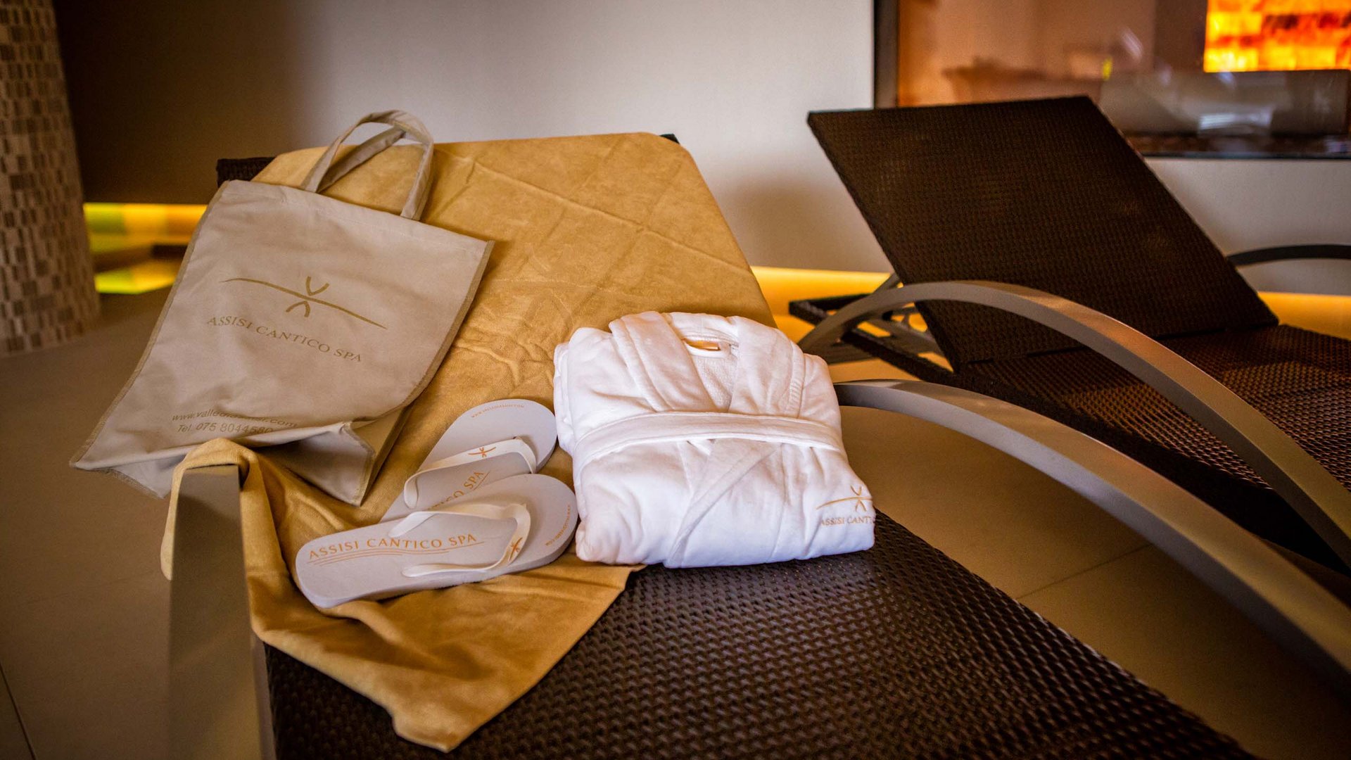 Una spa per bambini in Umbria? Eccola qui Assisi Cantico SPA a Santa Maria degli Angeli, la provincia di Perugia più bella! Accappatoio, ciabatte e borsa spa su lettino marrone in area relax
