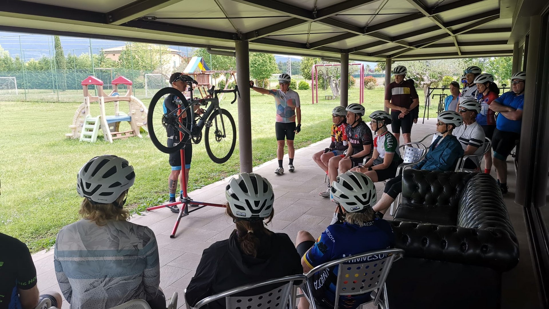 A holiday near Assisi: activities galore Group of cyclists with helmets attending an outdoor bike repair lesson
