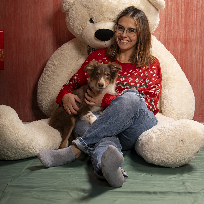 Ponte dell'Immacolata a Valle di Assisi Donna sorridente con maglione rosso che tiene un cucciolo seduta davanti a un grande orso di peluche