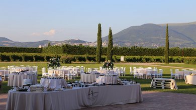 Perugia ha un Centro Meeting e Congressi d'eccezione: ai piedi di Assisi in Umbria Tavoli all'aperto apparecchiati per un evento in giardino con colline sullo sfondo
