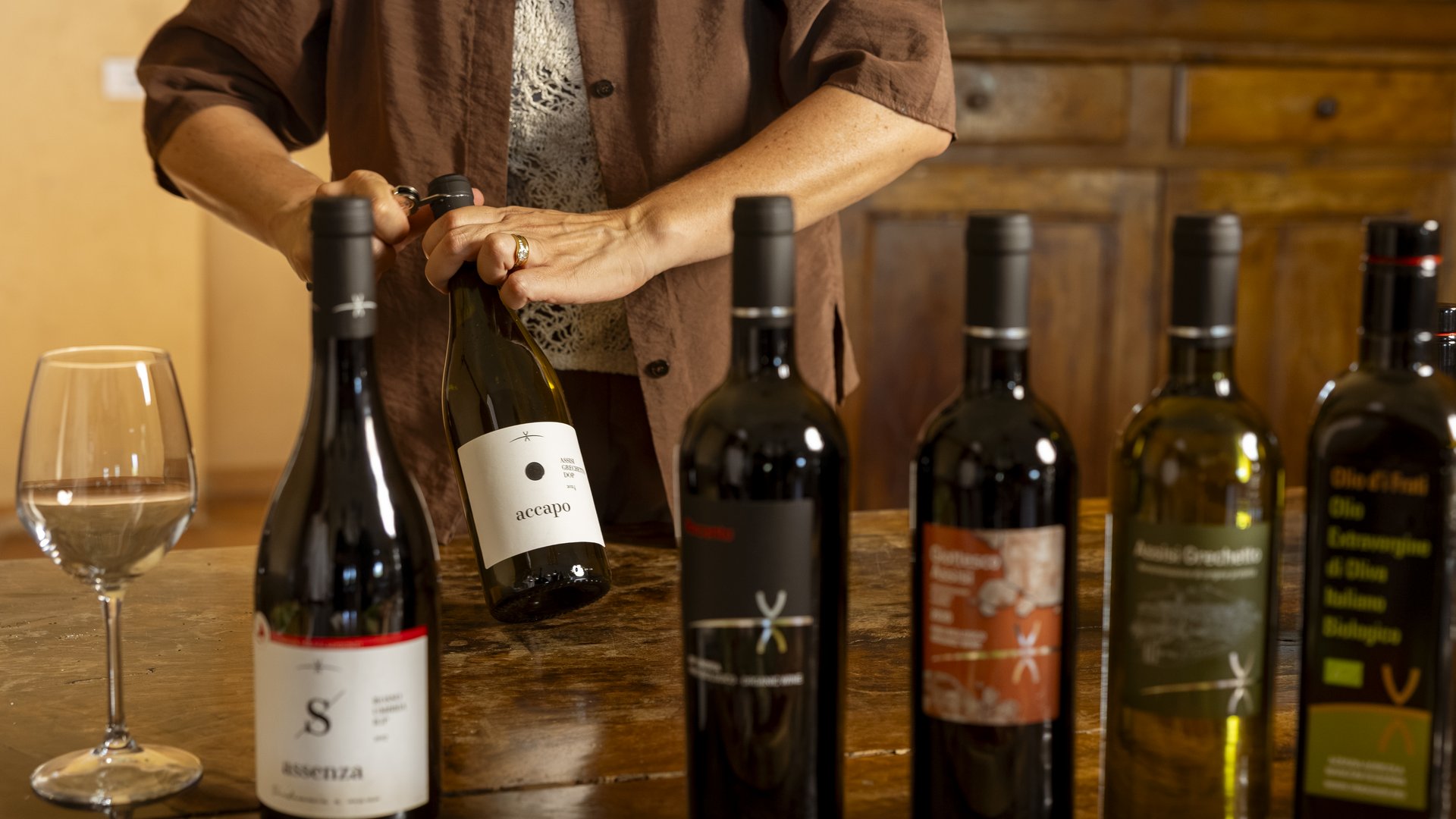 Un hotel vicino ad Assisi con mezza pensione da sogno Persona che apre una bottiglia di vino su un tavolo con altre bottiglie e un calice