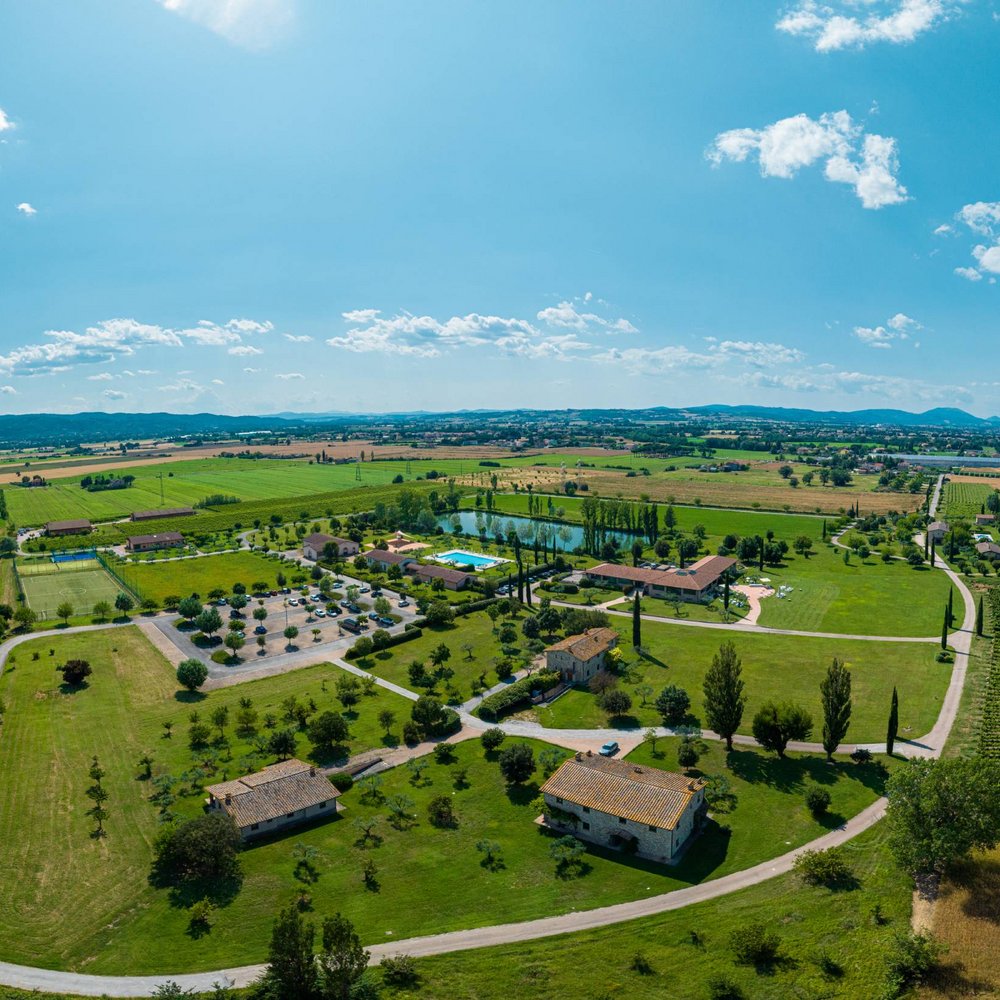 A Santa Maria degli Angeli - Assisi ( Perugia ) Centro Congressi e Meeting d'eccezione? I tuoi eventi vista Assisi Umbria Vista aerea di una campagna con edifici, campi verdi e piscina