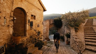 A holiday near Assisi: activities galore Cyclist riding through a historic stone alley at sunset