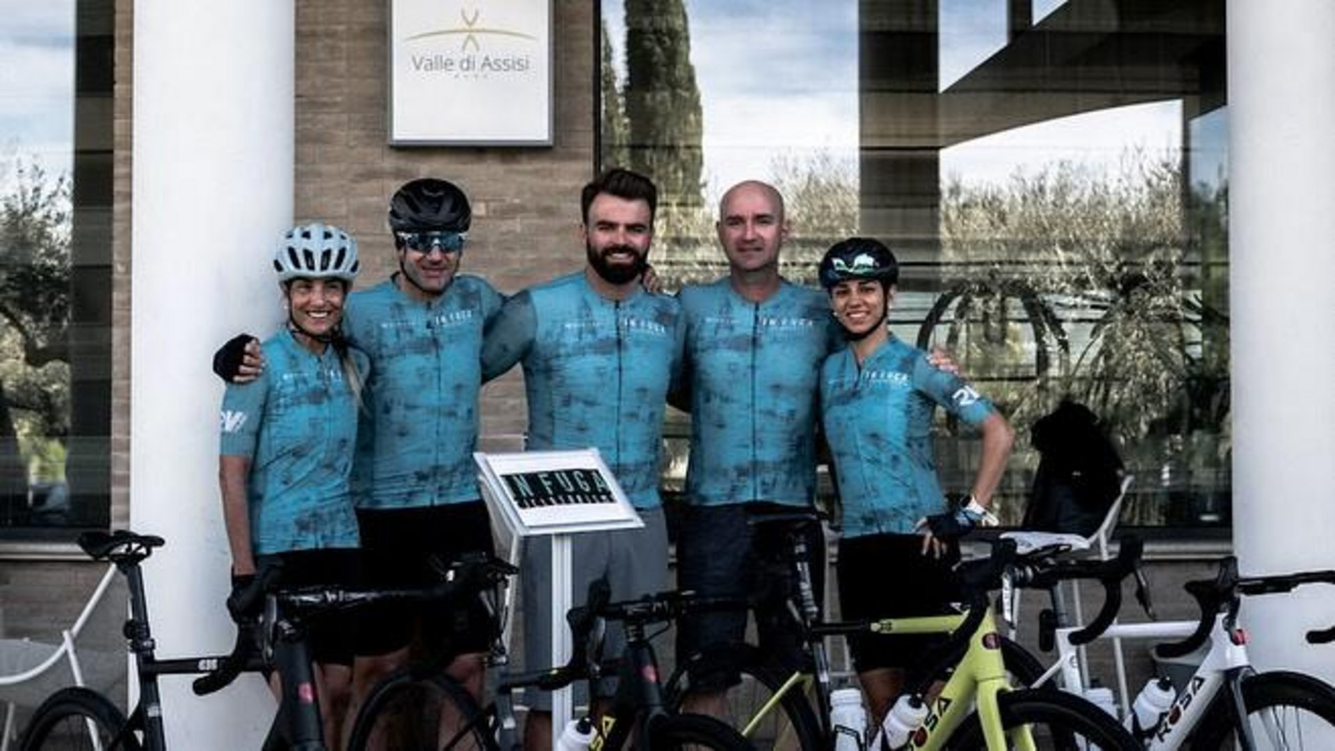 A holiday near Assisi: activities galore Group of cyclists in blue outfits posing in front of a building with bikes